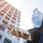 We must act smarter to solve air pollution crisis Man holding phone in front of tall building