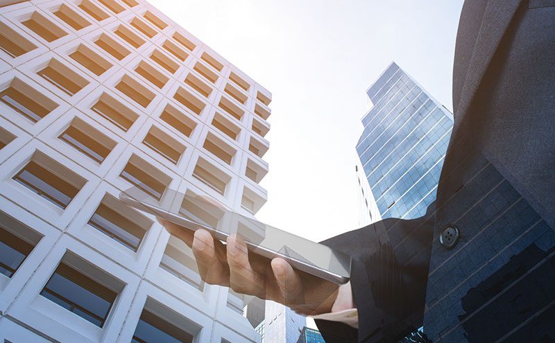 Man holding phone in front of tall building