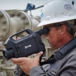 Inspecting pipelines with OGI man-holding-camcorder-on-site