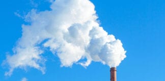 Pipe with white smoke against the background of blue sky and copy space. emission of steam and smoke into the atmosphere