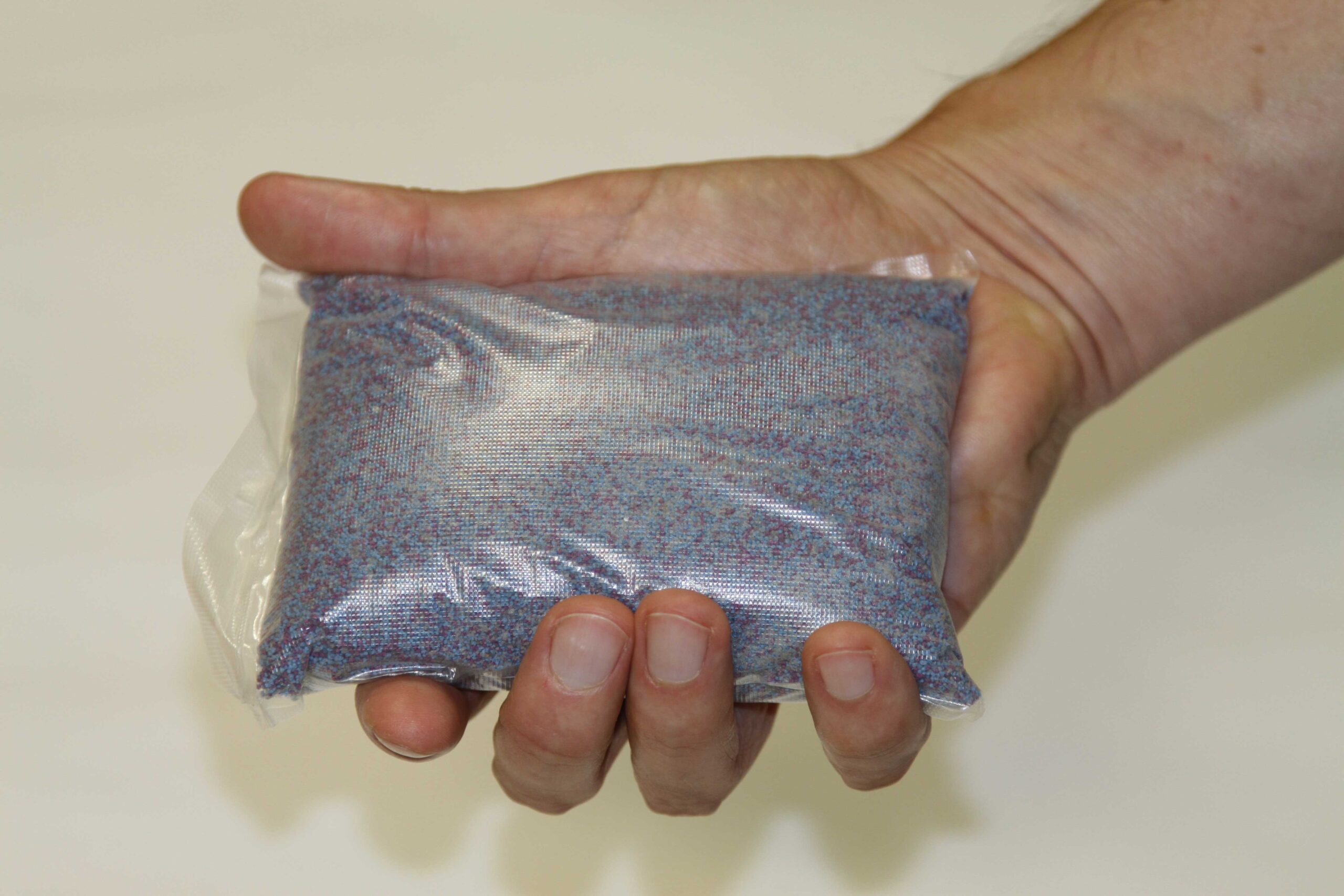 A hand holding a bag of grain-like substance 