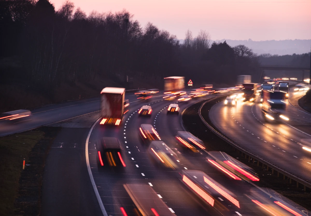 Traffic on a UK motorway at dusk, with vehicle headlights captured as continuous streaks of light