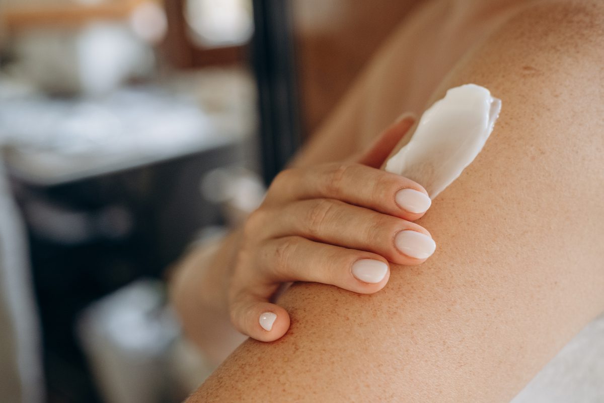 Womans arm with hand visible, applying skin cream