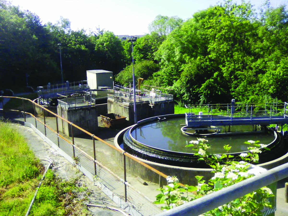 Wastewater treatment plant including circular tank, all in an outdoor, rural setting in sunlight