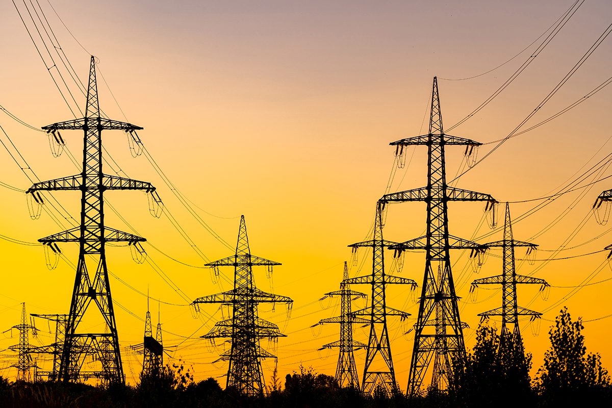 Electricity pylons against sunset sky