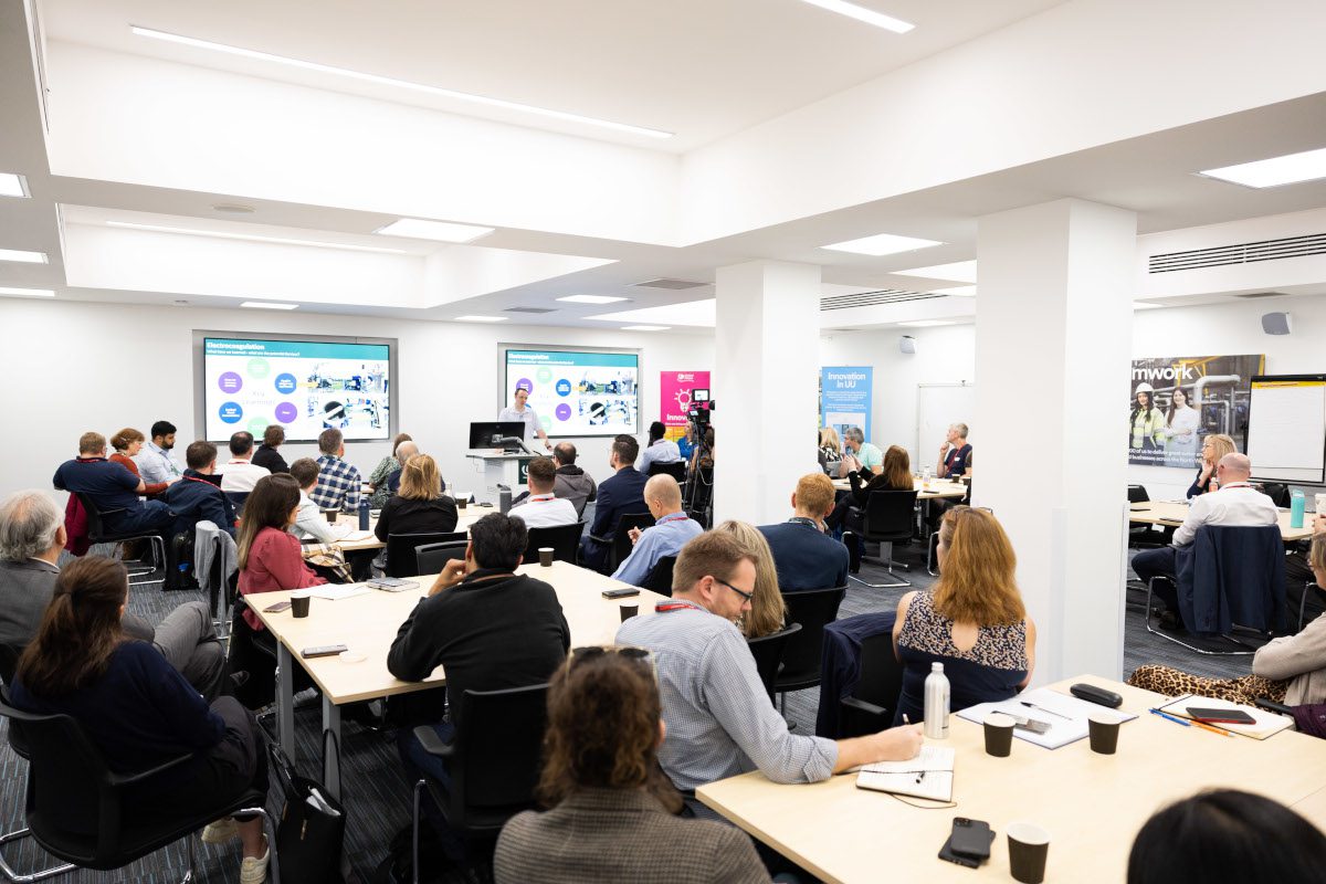 Room full of people sittting around tables, participating in ALT-P innovation day