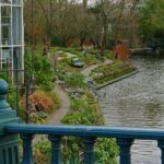 Why adding a fish pond to your landscaping can benefit you and the local environment A pond with blue fence and bench outside a glass building.