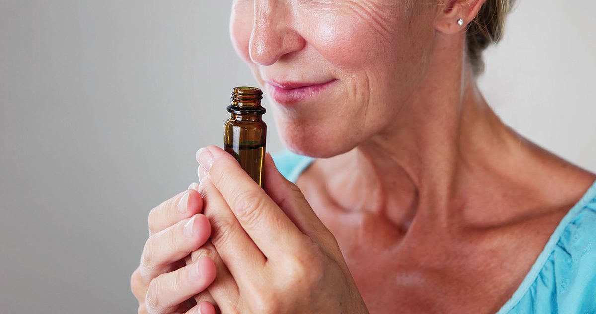 Woman sniffing from an aromatherapy jar, and smiling