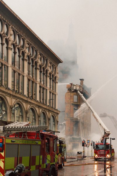 Daytime scene with firefighters applying hose jets to building in aftermath of fire