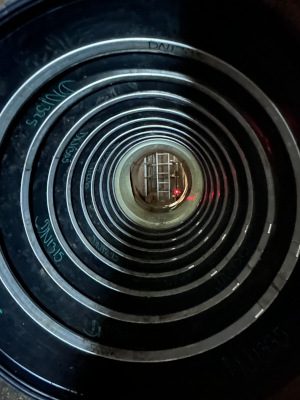 View down a large pipe showing multiple concentric lining rings installed inside, with a worker visible in the distance.