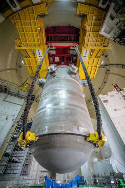 Viewed from below, the reactor pressure vessel is suspended by lifting gear beneath the yellow polar crane inside Hinkley Point C's Unit 2 reactor building