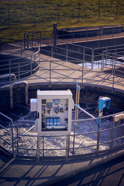 Water treatment monitoring equipment installed beside a circular settlement tank at a wastewater treatment plant