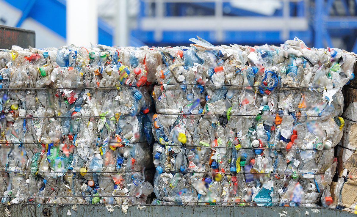 Stacks of compressed plastic bottles and containers in recycling facility on factory