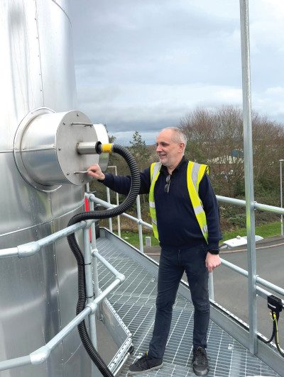Engineer inspecting the heated sample line connection on a regenerative thermal oxidiser (RTO) emissions monitoring system from an elevated access platform at an industrial site
