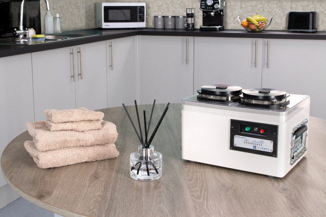 Automated VOC sampling instrument on a table beside a reed diffuser and folded towels in a kitchen setting