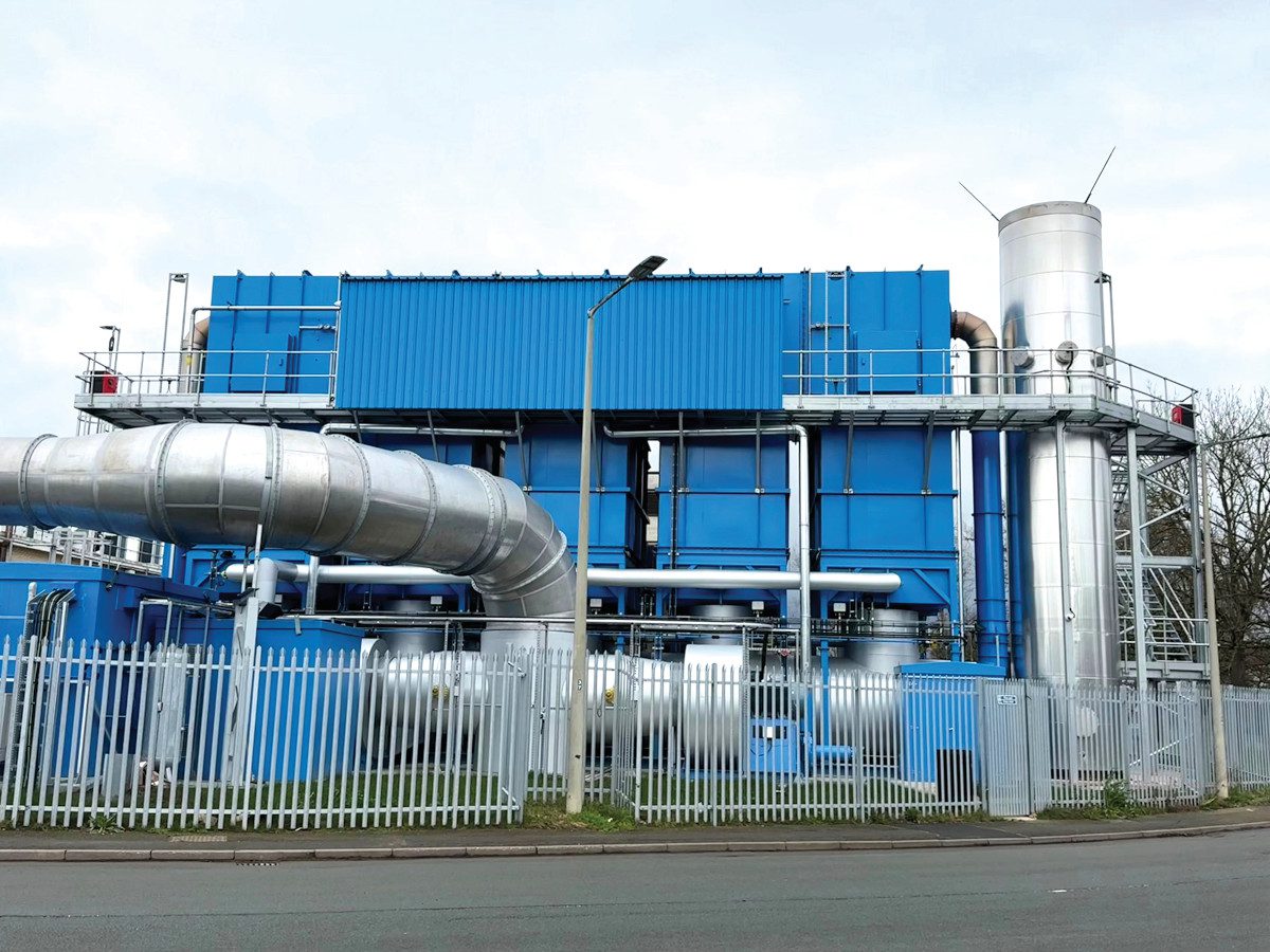 Industrial regenerative thermal oxidiser (RTO) with large ventilation ductwork, exhaust stack and access platforms at a fenced manufacturing facility