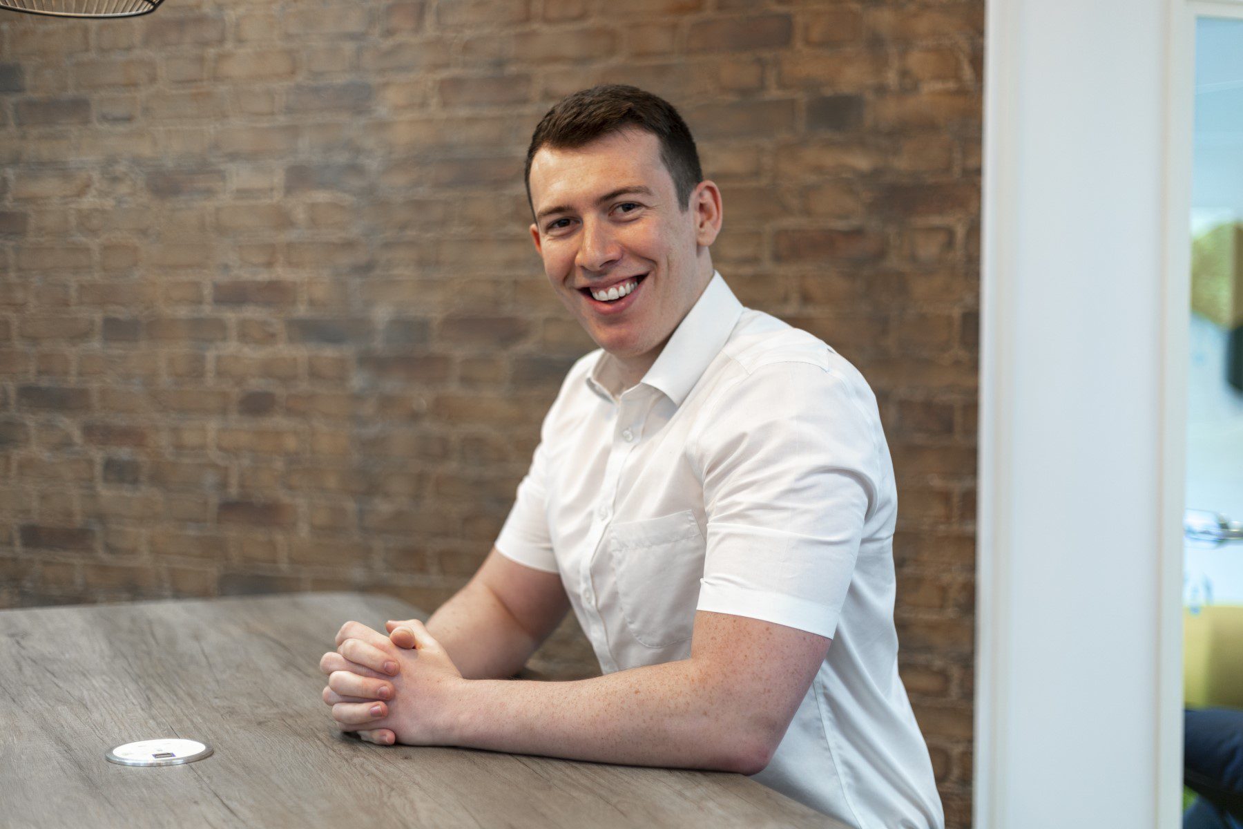 Matthew Partridge, Head of Product Development at Armorgard UK, seated at a meeting table in a white shirt, smiling towards the camera